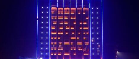 Un hotel de varios pisos con una torre central y señalización iluminada.