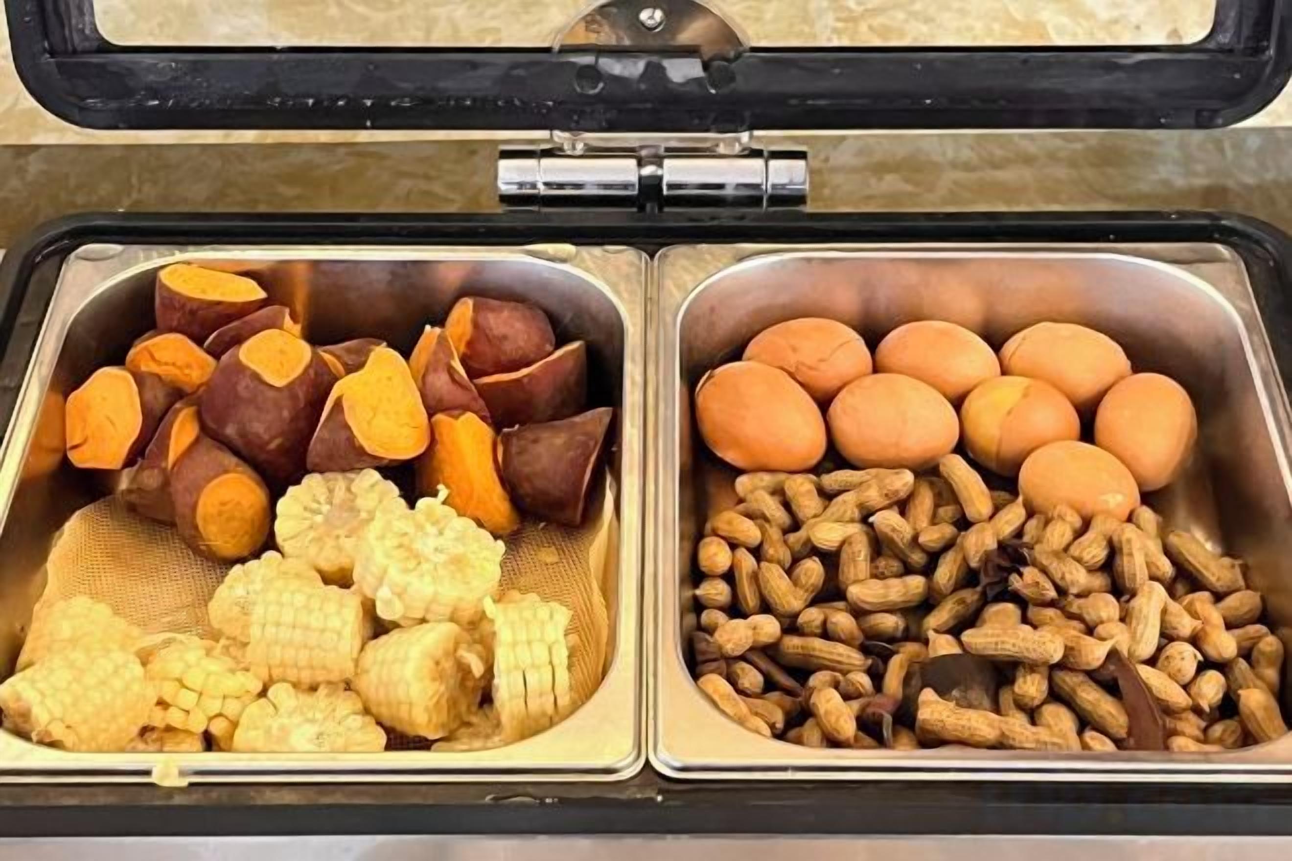 A food buffet with sweet potatoes, corn, and peanuts.