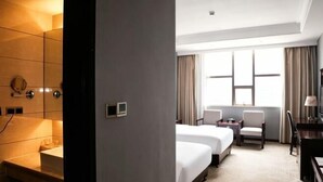 A hotel room with a bed, a desk, a chair, a mirror, and a window with curtains. - Nantian Hotel (Shangli)