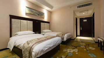 Una habitación de hotel con dos camas, un cuadro grande en la pared y una alfombra estampada con motivos florales.