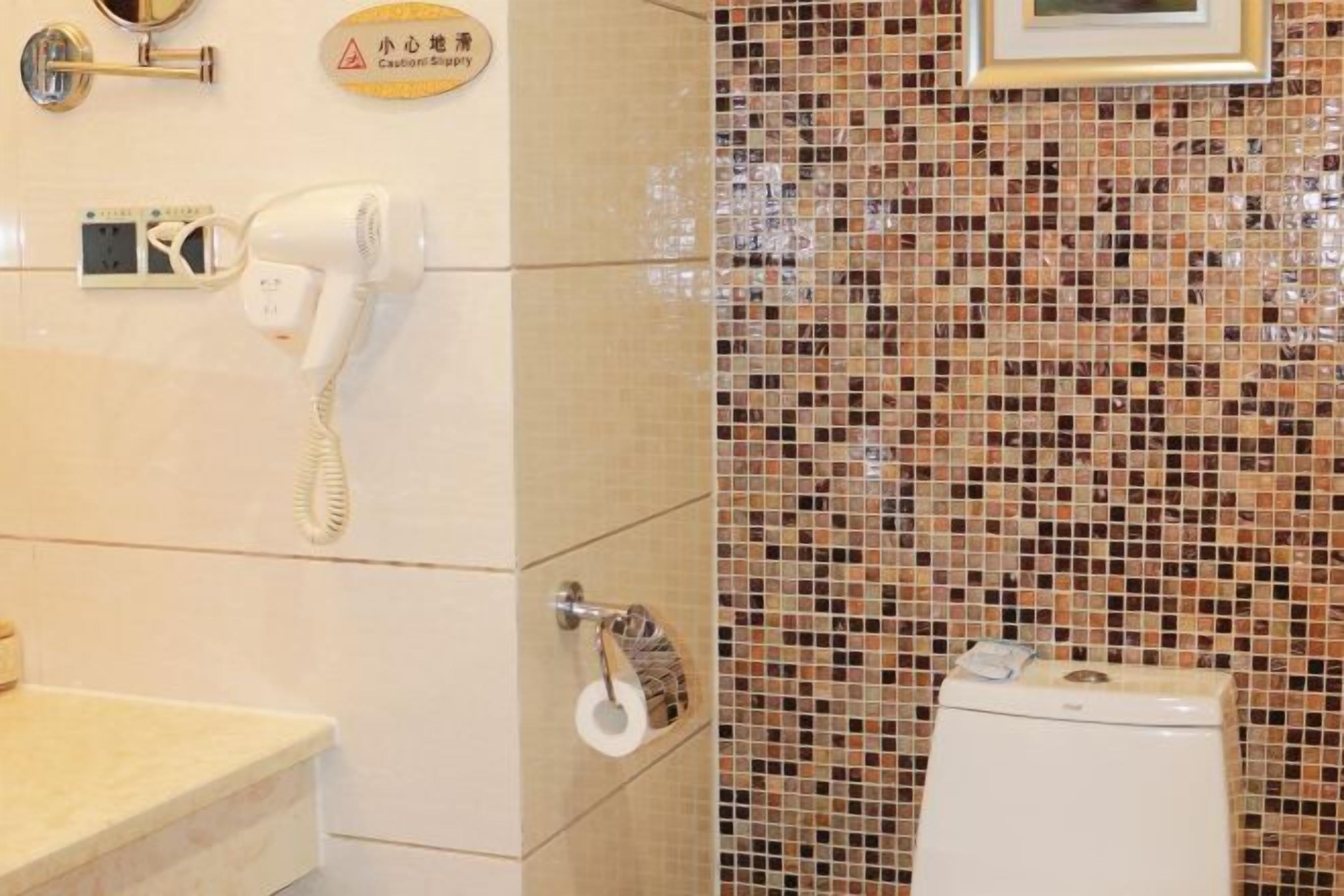 Un baño con un inodoro blanco, un secador de manos, un espejo y un letrero de precaución.