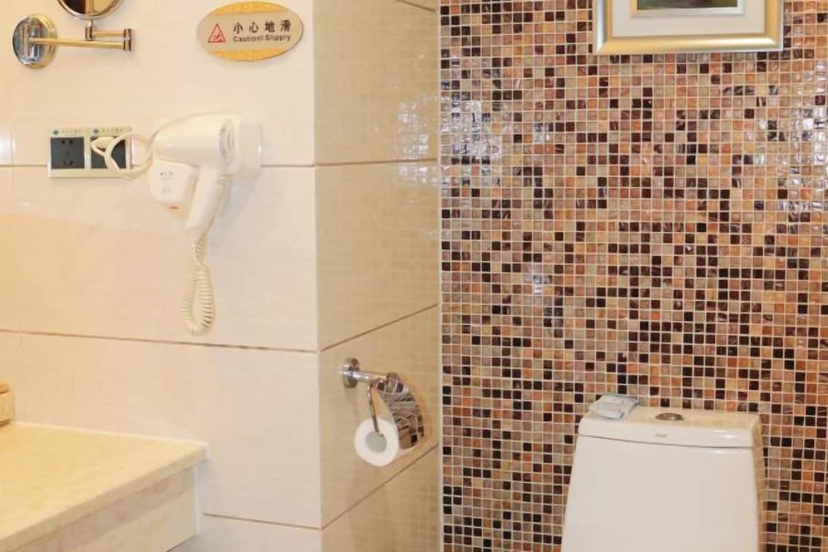 Un baño con un inodoro blanco, un secador de manos, un espejo y un letrero de precaución.