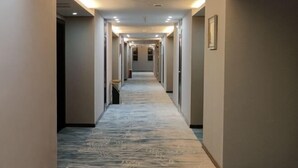 A long, narrow hallway with a patterned carpet, recessed lighting, and a framed picture on the wall. - Nantian Hotel (Shangli)
