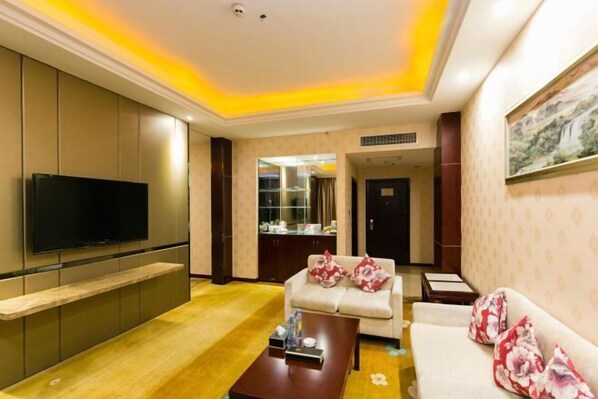 A modern living room with a flat-screen TV, a sofa, a coffee table, and a cabinet. - Nantian Hotel (Shangli)