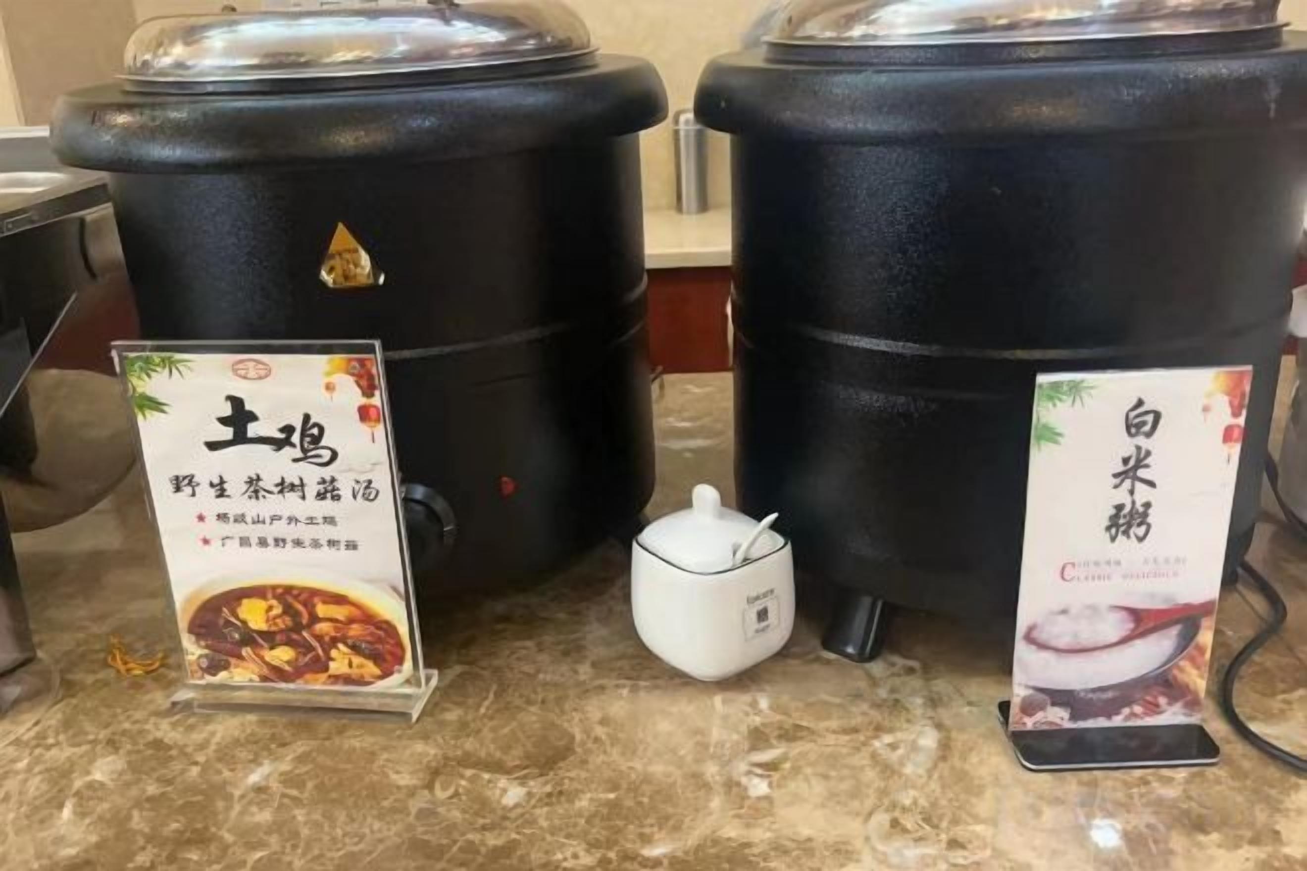 Deux récipients noirs dotés de couvercles, un petit pichet blanc et deux panneaux d’information avec du texte en chinois.