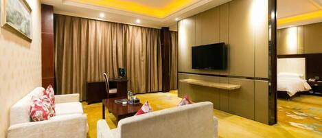 Una habitación de hotel con sofá, televisor, escritorio y cama.