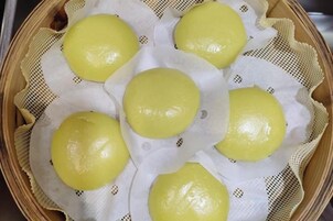 Una canasta con bollos al vapor amarillos.
