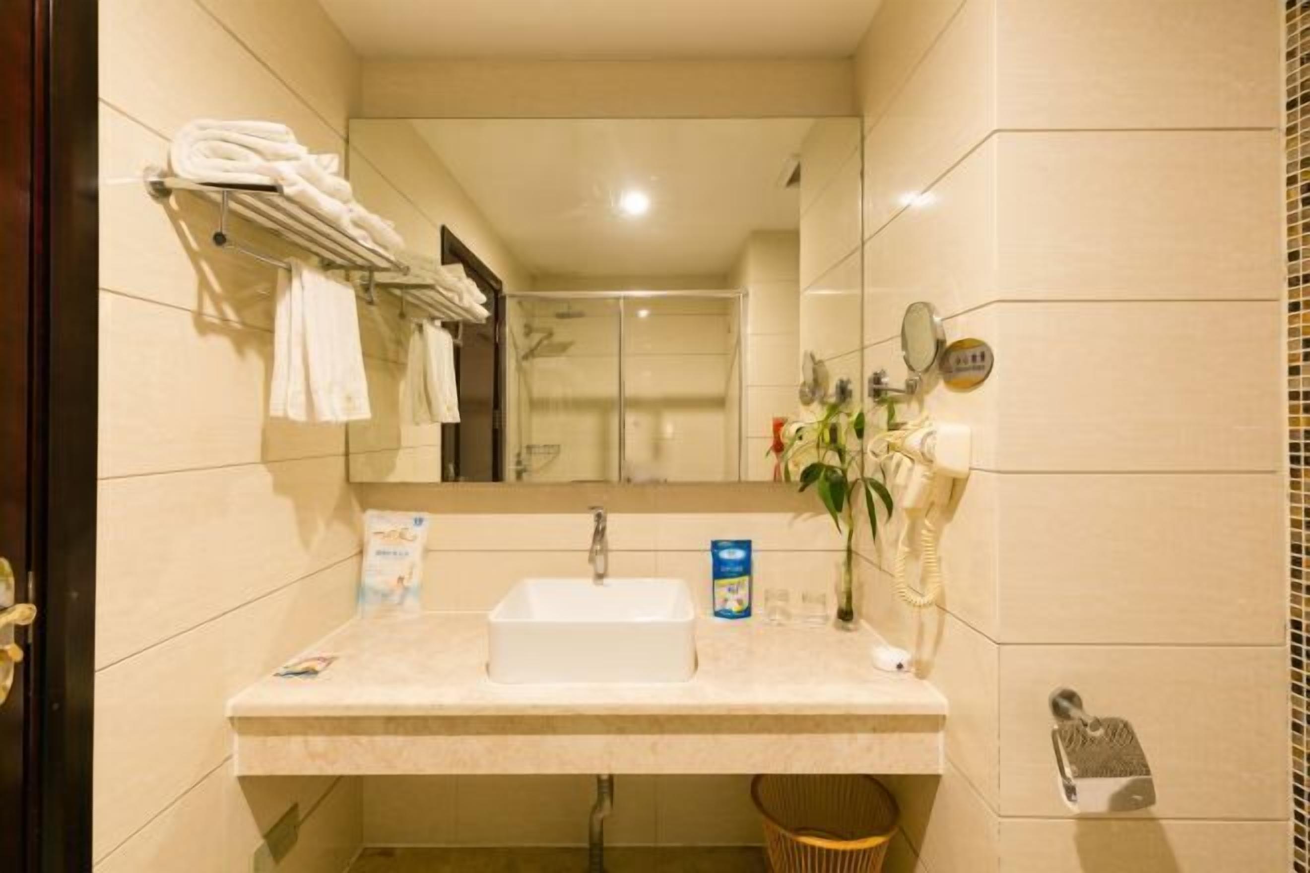 Un baño de hotel con lavamanos, espejo, toallero y teléfono.