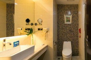 A bathroom with a large mirror, a sink, a toilet, and a shower area. - Nantian Hotel (Shangli)