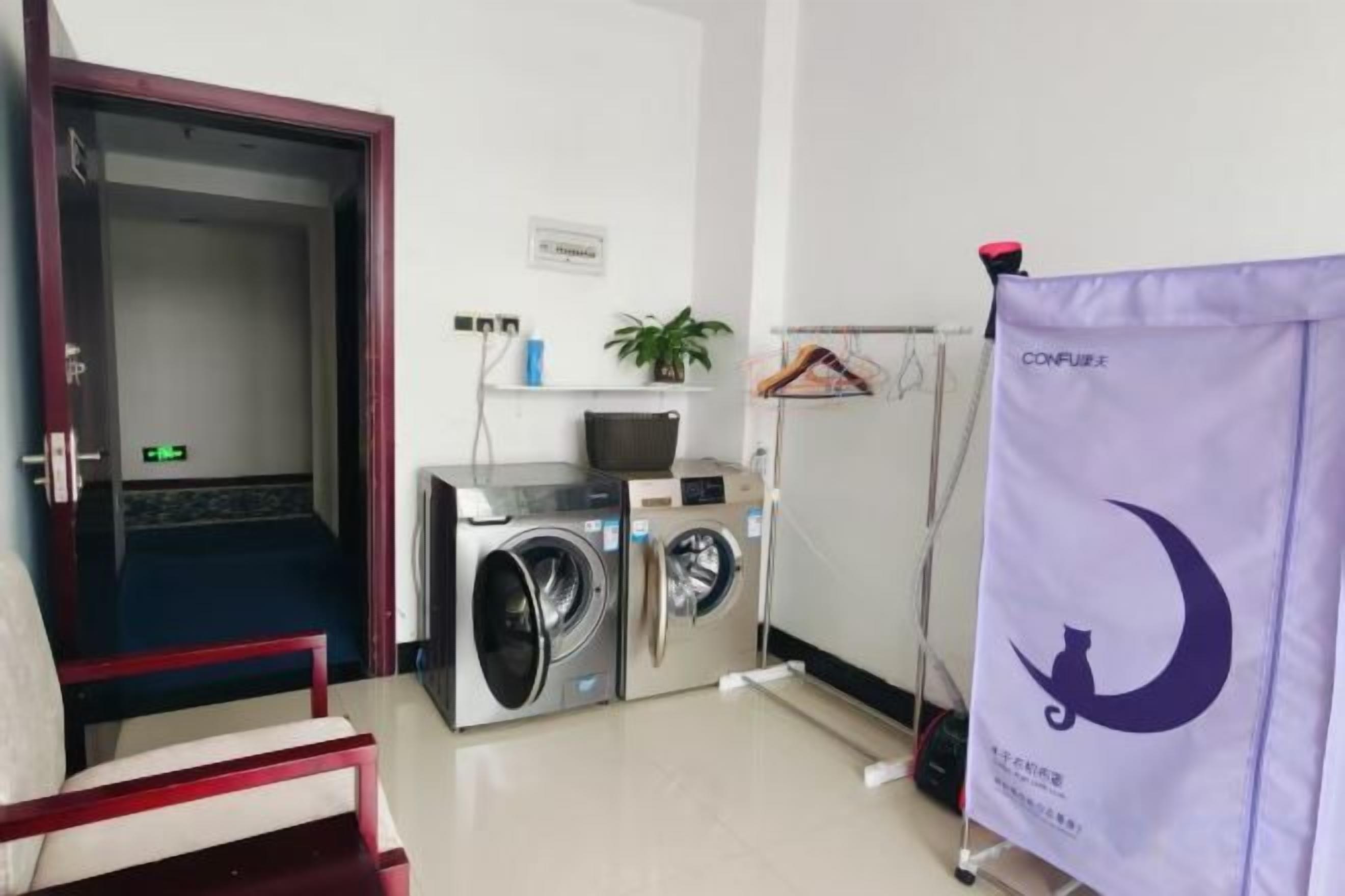 A laundry area with a washing machine and dryer, a door, a potted plant, and a purple banner.