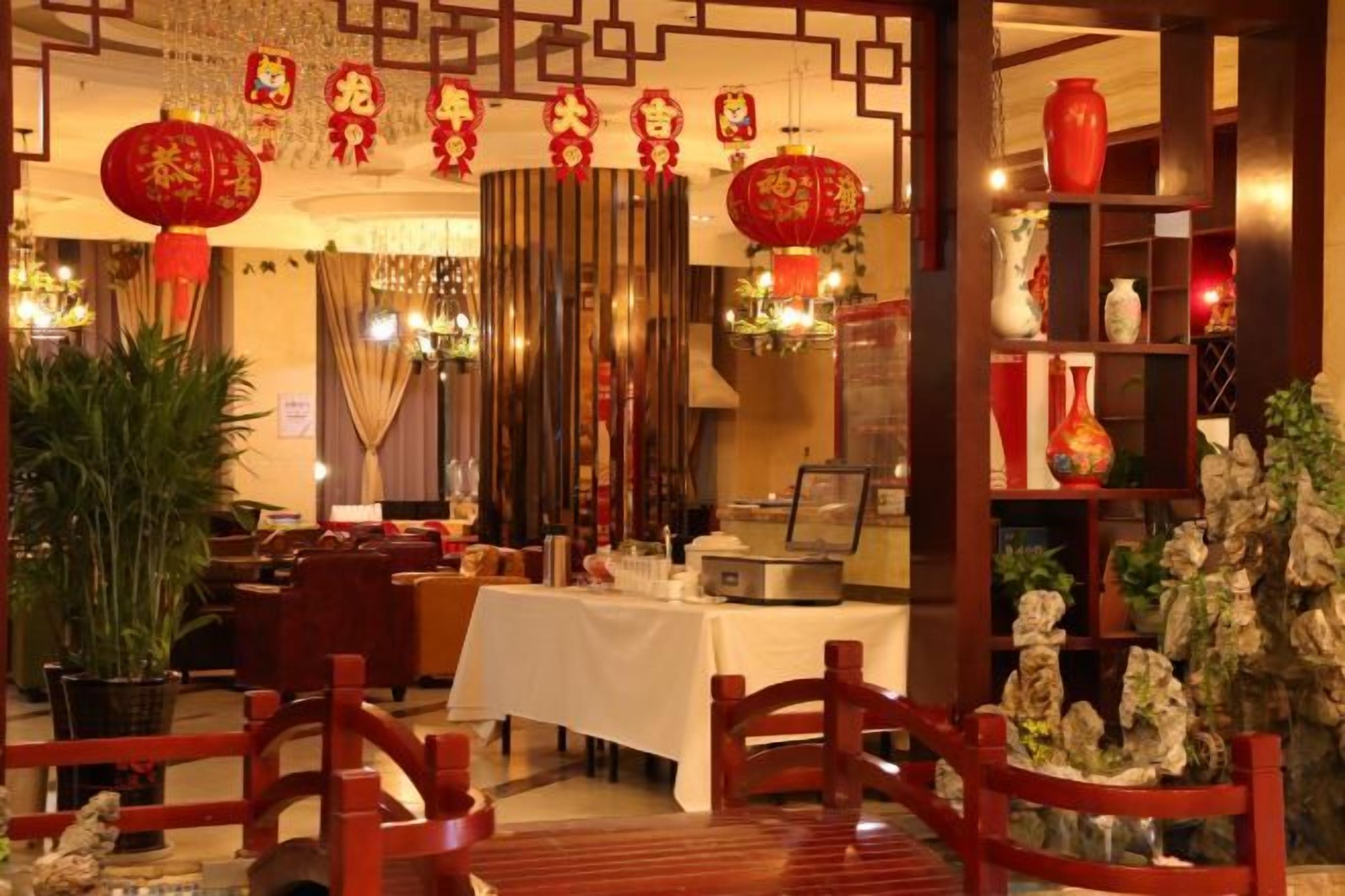 A traditional Chinese restaurant interior with wooden furniture, red lanterns, and a table set for dining.