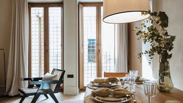 A dining area with a table set for four, a chair, a lamp, and a vase with flowers.