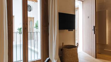A room with a sliding glass door leading to a balcony, a mounted TV, and a woven basket on the floor.