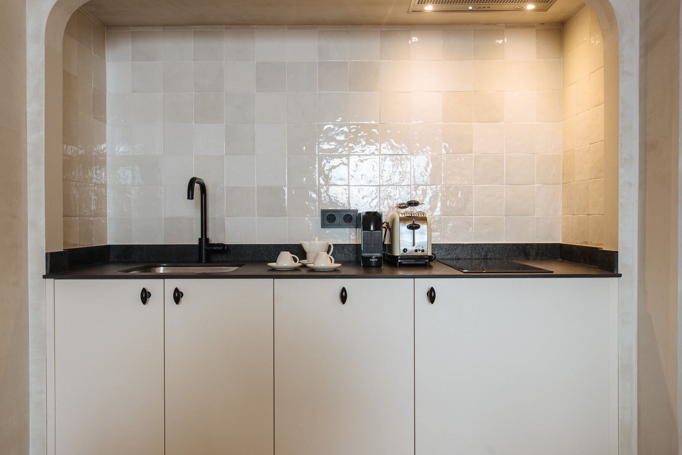 A kitchen with a black countertop, a sink, and a coffee maker.
