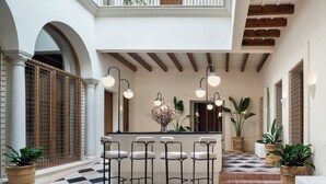 A bar area with a checkered floor, bar stools, and pendant lighting. -  Casa del Rey Sabio (Seville)