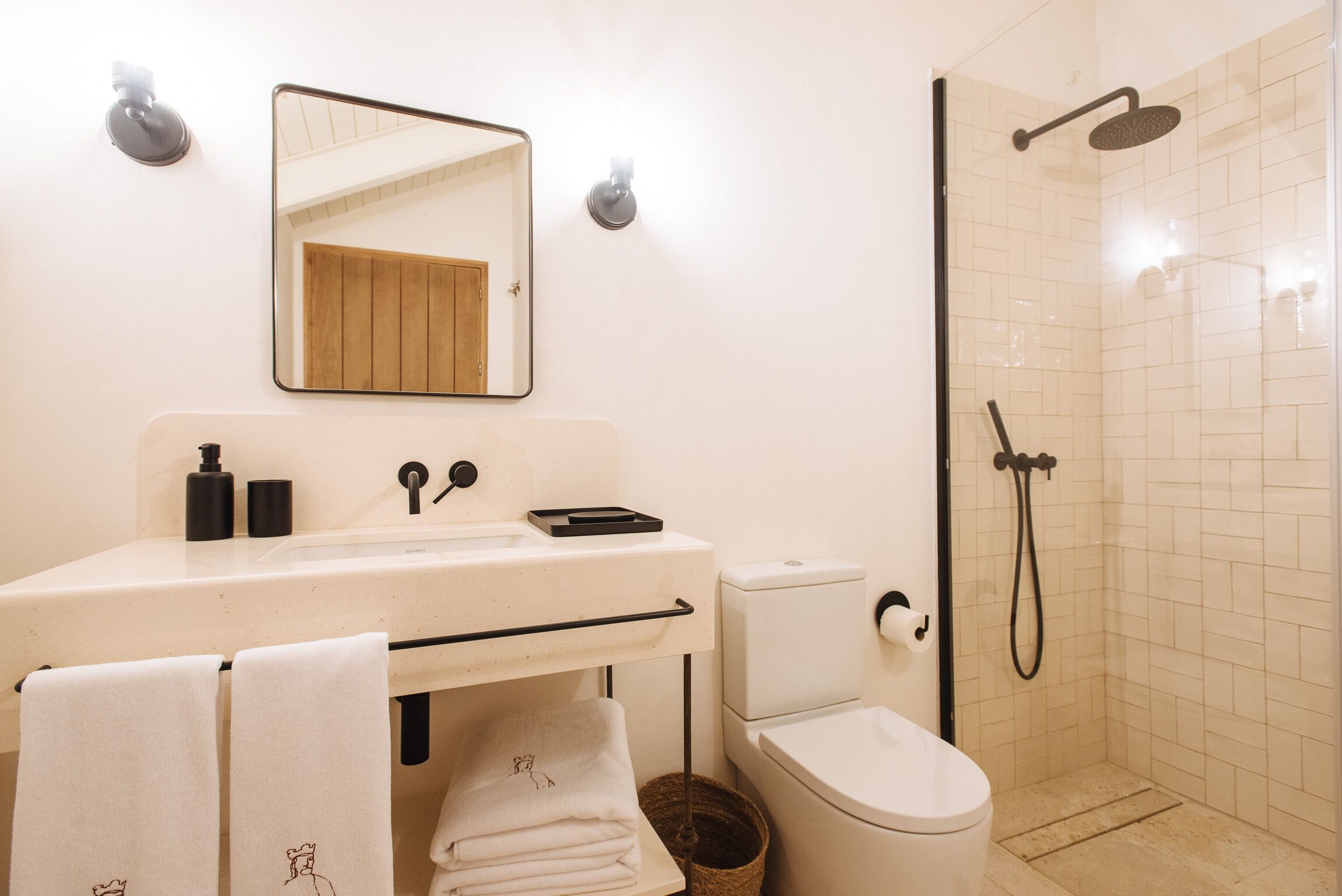 A bathroom with a sink, mirror, toilet, and shower.