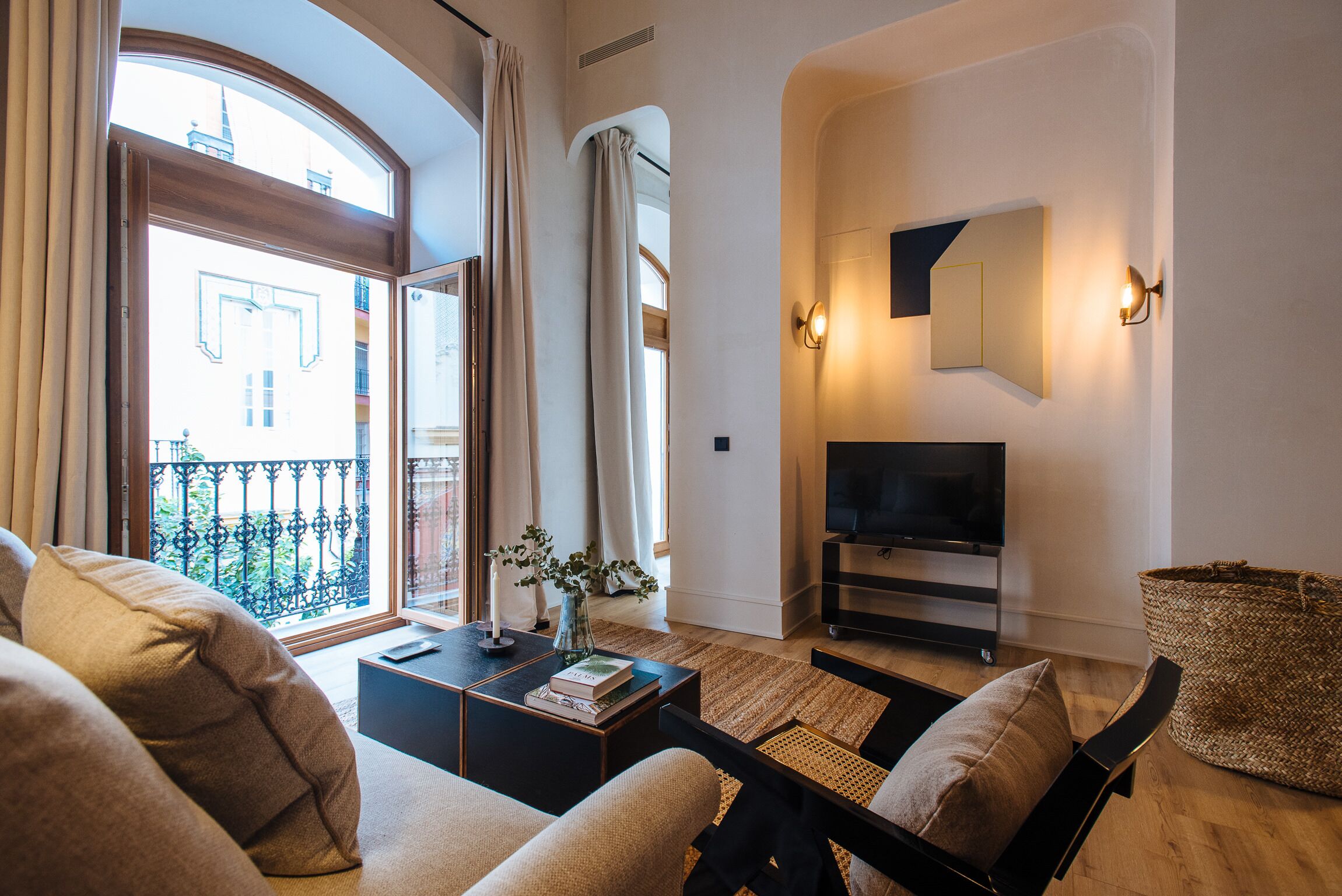 A modern living room with a sofa, coffee table, TV, and a balcony view.