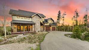 A two-story house with a stone facade, a covered porch, and a driveway leading to a garage. - Luxury Home - Incredible Views! Fireplace, Multiple Decks & Hiking from the Property (Grand Lake)
