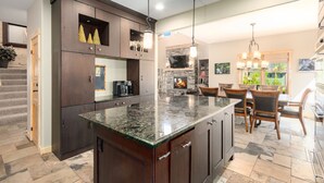 A modern kitchen with dark wood cabinets, a granite countertop, and a stone fireplace. - Luxury Home - Incredible Views! Fireplace, Multiple Decks & Hiking from the Property (Grand Lake)