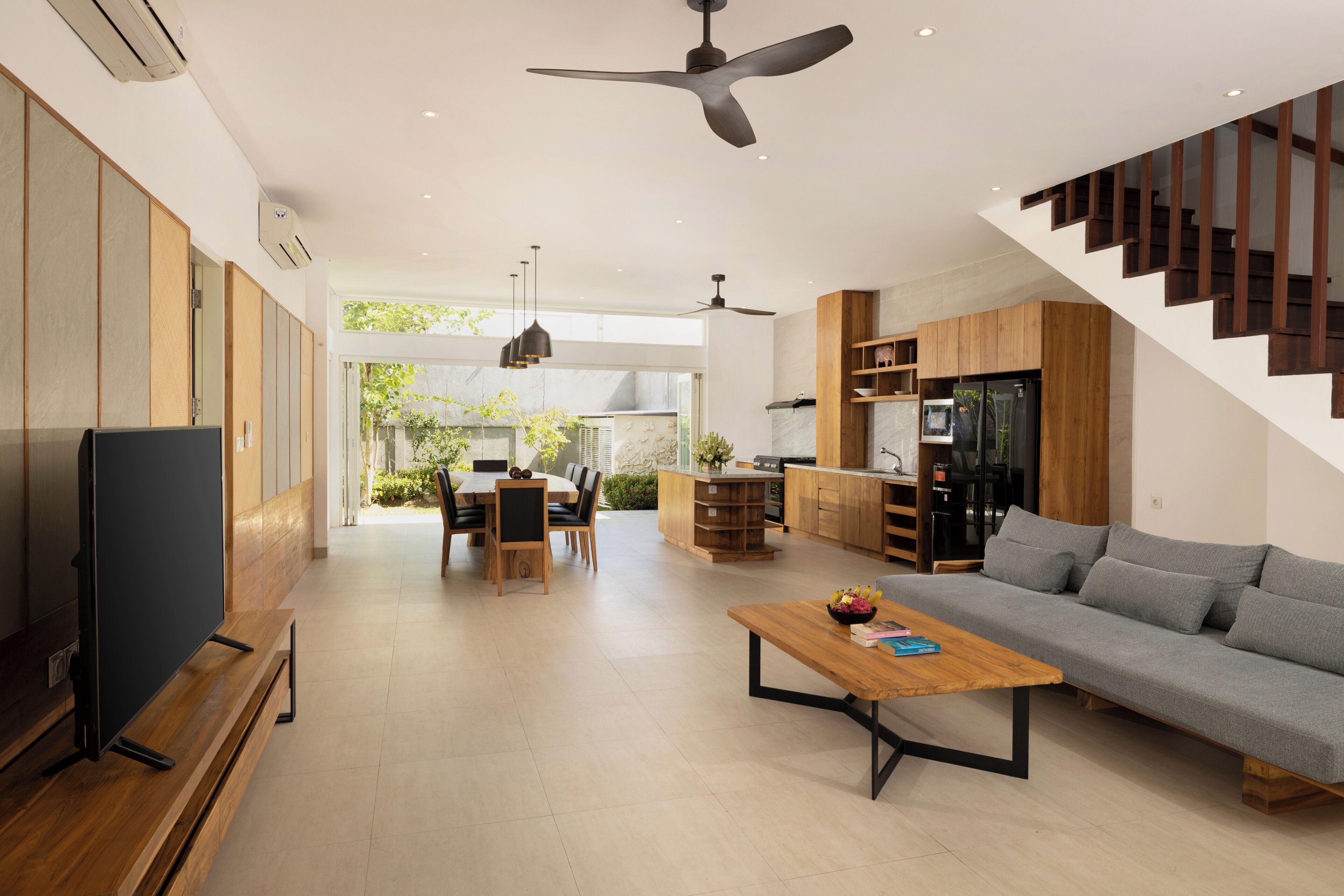A modern living room with a flat-screen TV, a sofa, a coffee table, and a dining area with a table and chairs.