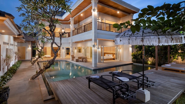 A multi-story resort with a swimming pool, outdoor seating, and a covered area with a thatched roof. - Villa Christie by Nakula (Seminyak)