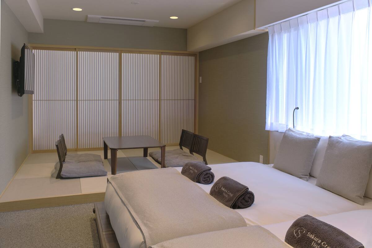 A hotel room with a bed, a desk, a chair, and a TV on the wall.