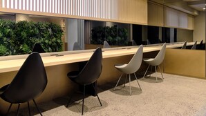 A modern office space with a long table, several chairs, and a green plant wall.