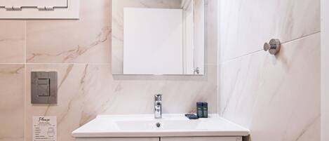 A bathroom with a white sink, a mirror, and a toilet. There is a sign on the wall with instructions.