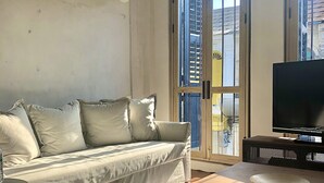 Ein Wohnzimmer mit einem weißen Sofa, einem Holztisch, einem Fernseher und einem gemusterten Teppich.