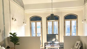 Ein Schlafzimmer mit Bett, Nachttisch, Pflanze, Fernseher und Schreibtisch mit Stuhl.