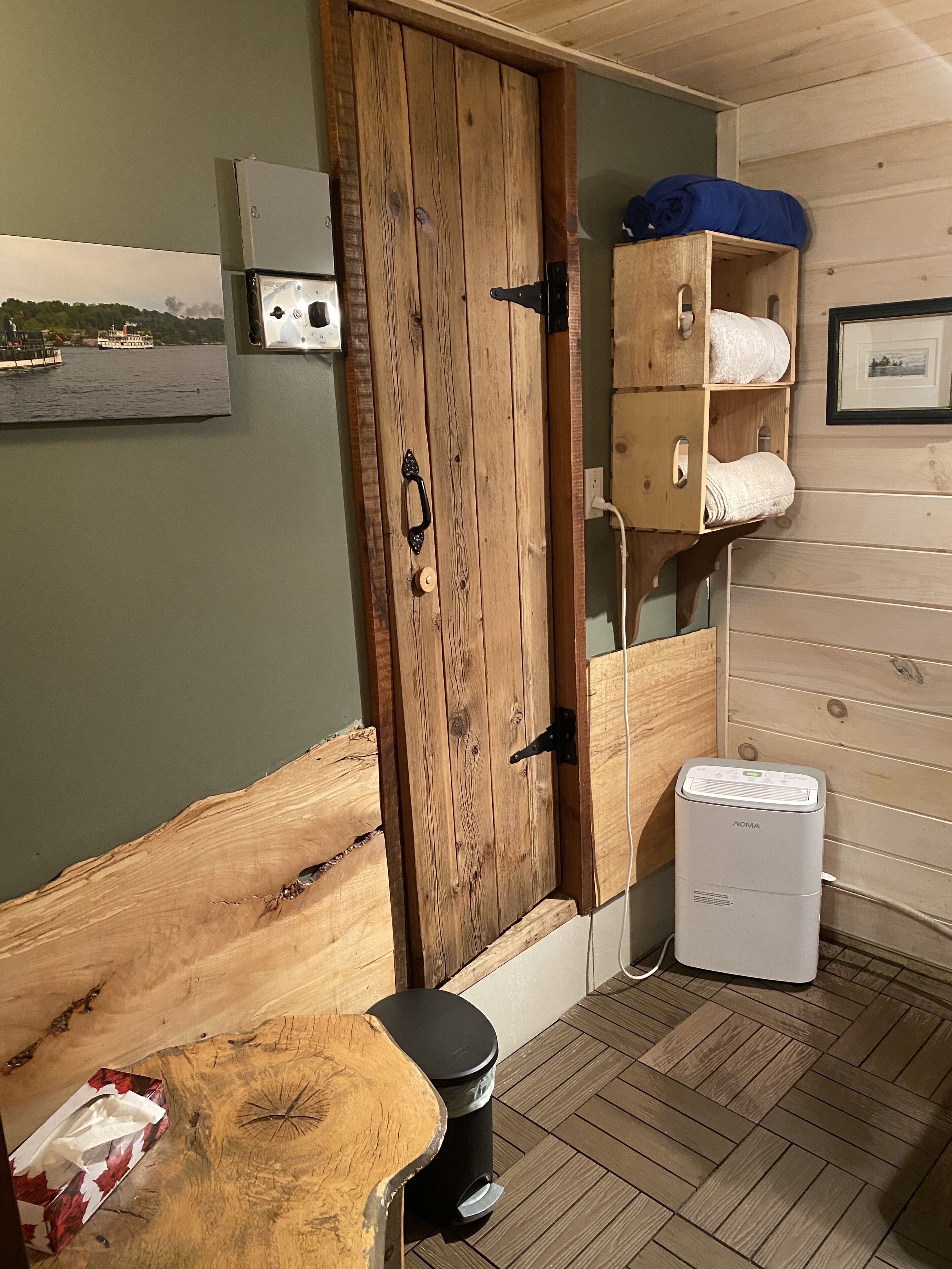 Uma sala de sauna com porta de madeira, um banco, um suporte para toalhas e um pequeno aquecedor.