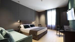 Una habitación de hotel moderna con una cama grande, un escritorio, una silla y un sofá.