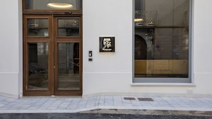 Entrada de un hotel con puerta de madera y un amplio ventanal.