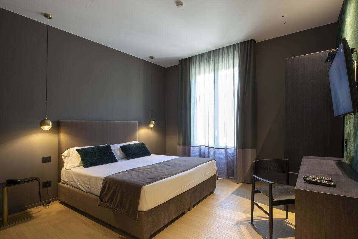 A modern hotel room with a large bed, a desk, and a chair.
