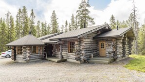 A log cabin with a chimney, wooden door, and windows. - Rukan Salonki Chalets (Kuusamo)
