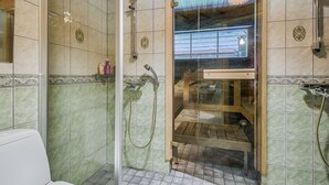 A shower area with a glass door, tiled walls, and a wooden ceiling. - Rukan Salonki Chalets (Kuusamo)