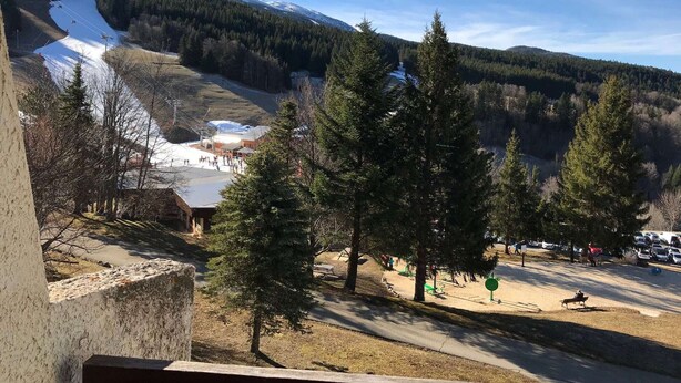 A mountainous landscape with a ski slope, a small lodge, and a parking area with trees. - Family studio near slopes, parking, Villard-de-Lans (Villard-de-Lans)