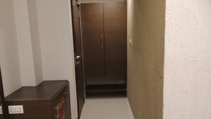 Un couloir étroit, avec une armoire en bois sur le côté gauche et une porte au fond.