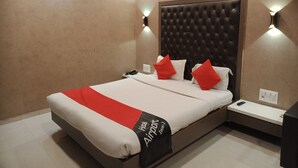 Une chambre d’hôtel avec un grand lit, une tête de lit, des tables de chevet et un luminaire fixé au mur.