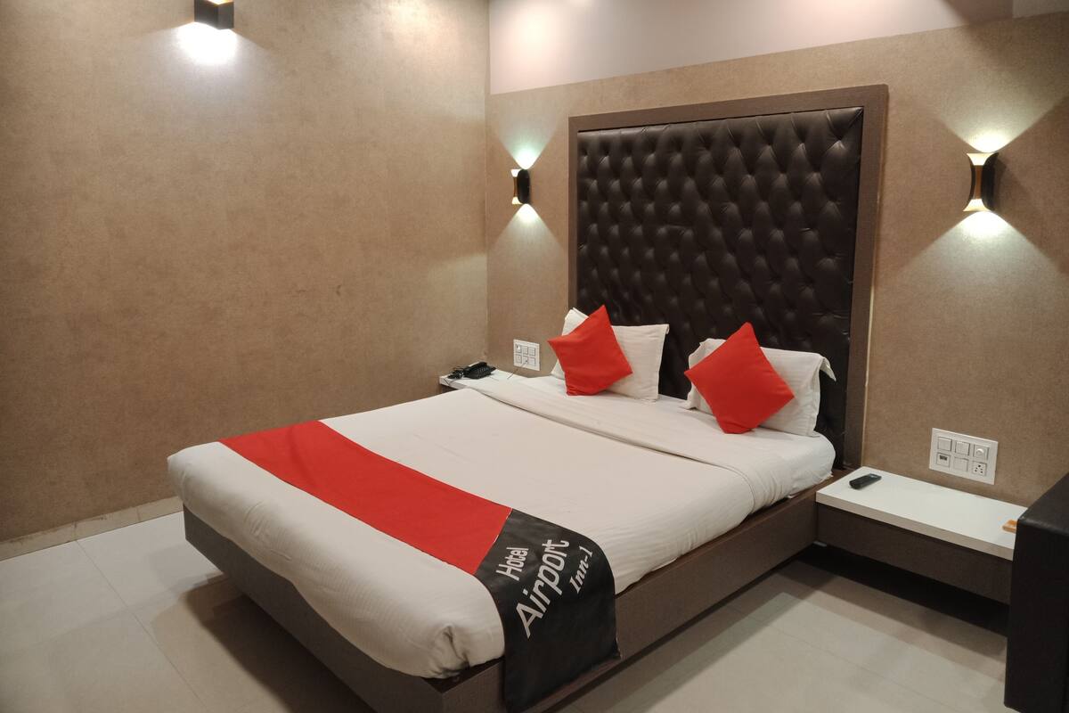 Ein Hotelzimmer mit einem großen Bett, einem Kopfteil, Nachttischen und einer wandmontierten Leuchte.