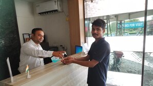 Un comptoir d’accueil avec une cloison en verre, une pancarte indiquant « VENTE DE BILLETS », et une vue sur l’extérieur à travers le verre.