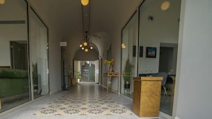 A hallway with a patterned floor, a wooden podium, and a staircase in the background.