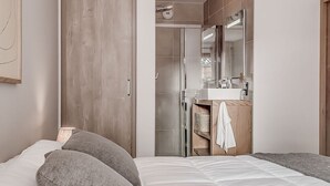 Un dormitorio con cama, armario y baño visible a través de una puerta abierta.
