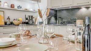 Una cocina moderna con gabinetes blancos, un protector contra salpicaduras negro y diversos electrodomésticos.