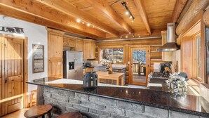 A spacious kitchen with wooden cabinets, a granite countertop, and a stone wall.