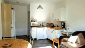 Ett kompakt kök med mikrovågsugn, kaffebryggare och ett litet matbord.