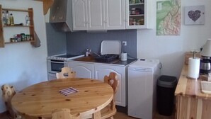 A compact kitchen with white cabinets, a wooden dining table, and a coffee machine. - Studio in Corrençon-en-Vercors, 4 pers, pets allowed (Corrençon-en-Vercors)