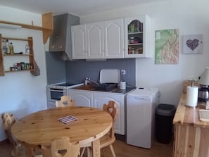 A compact kitchen with white cabinets, a wooden dining table, and a coffee machine. - Studio in Corrençon-en-Vercors, 4 pers, pets allowed (Corrençon-en-Vercors)