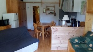 A compact living space with a sofa, a dining table with chairs, a kitchenette, and a wooden cabinet. - Studio in Corrençon-en-Vercors, 4 pers, pets allowed (Corrençon-en-Vercors)