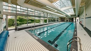 An indoor swimming pool with clear glass walls, a tiled floor, and a high ceiling with visible ductwork. - Ocean, Mountain, City Views, Fully Furnished, Downtown Vancouver (Vancouver)
